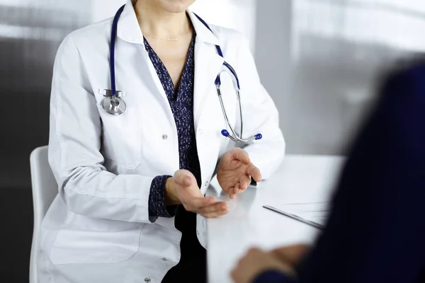 Une femme-médecin inconnue parle à sa patiente de son diagnostic, alors qu'elle est assise ensemble au bureau dans l'armoire d'une clinique. Médecin sur le lieu de travail, gros plan. Service médical parfait dans un — Photo