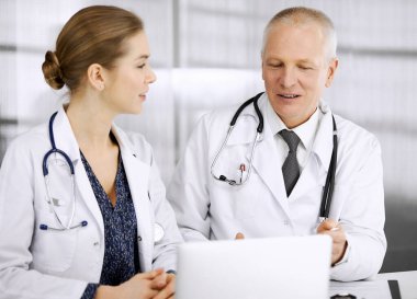 Yaşlı doktor ve bayan meslektaşı klinikte çalışırken güncel hastalık terapisini tartışıyorlar. Hastanede takım çalışması. Tıp ve sağlık hizmetleri kavramı