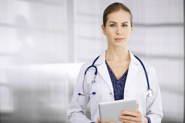 Allegro dottore donna in piedi in clinica. Ritratto di amichevole sorridente medico donna. Servizio medico perfetto in ospedale. Concetto di medicina — Foto Stock