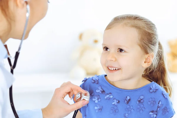 Lekarz badający małą dziewczynkę stetoskopem. Szczęśliwy, uśmiechnięty pacjent na zwykłej inspekcji medycznej. Medycyna i koncepcje opieki zdrowotnej — Zdjęcie stockowe