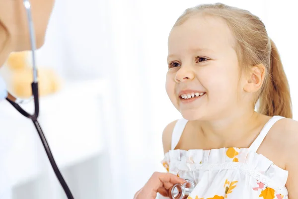 Docteur examinant une petite fille par stéthoscope. Heureux enfant patient souriant à l'inspection médicale habituelle. Médecine et concepts de santé — Photo