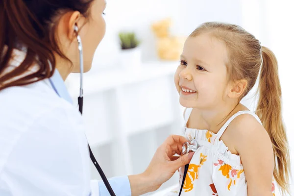 Doutor examinando uma menina por estetoscópio. Paciente de criança sorridente feliz em inspeção médica habitual. Conceitos de medicina e saúde — Fotografia de Stock