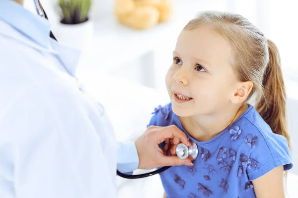 Doutor examinando uma menina por estetoscópio. Paciente de criança sorridente feliz em inspeção médica habitual. Conceitos de medicina e saúde — Fotografia de Stock