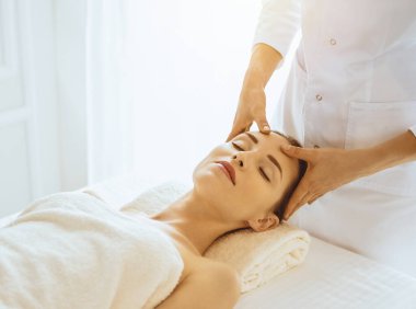 Güneşli spa merkezinde yüz masajından hoşlanan güzel bir kadın. Tıpta rahatlatıcı tedavi kavramı