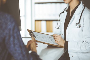 Doktor ve hasta klinikte otururken sağlık muayenesini tartışıyorlar. Hastanede mükemmel bir tıbbi hizmet.