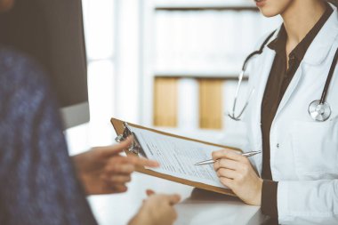 Doktor ve hasta klinikte otururken sağlık muayenesini tartışıyorlar. Hastanede mükemmel bir tıbbi hizmet.