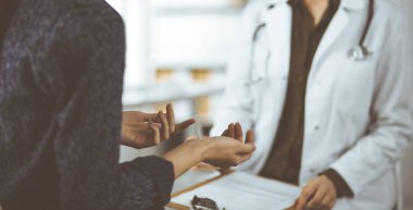 Doktor ve hasta klinikte otururken sağlık muayenesini tartışıyorlar. Hastanede mükemmel bir tıbbi hizmet.