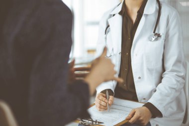 Doktor ve hasta klinikte otururken sağlık muayenesini tartışıyorlar. Hastanede mükemmel bir tıbbi hizmet.