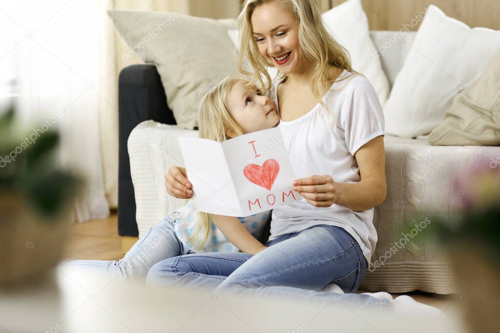 Happy mother day. Child daughter congratulates mom and gives her postcard with heart drawing. Family and childhood concepts