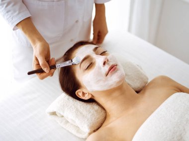 Güzel esmer kadın kapalı gözlerle kozmetik maske takmaktan zevk alıyor. Tıp ve kaplıca merkezi kavramlarında rahatlatıcı tedavi