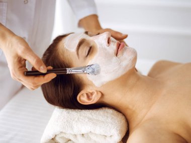 Güzel esmer kadın kapalı gözlerle kozmetik maske takmaktan zevk alıyor. Tıp ve kaplıca merkezi kavramlarında rahatlatıcı tedavi