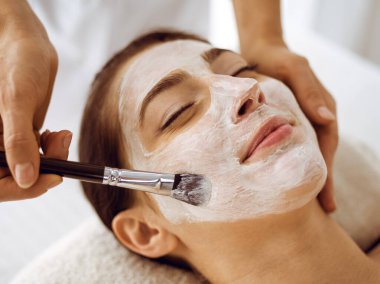 Güzel esmer kadın kapalı gözlerle kozmetik maske takmaktan zevk alıyor. Tıp ve kaplıca merkezi kavramlarında rahatlatıcı tedavi