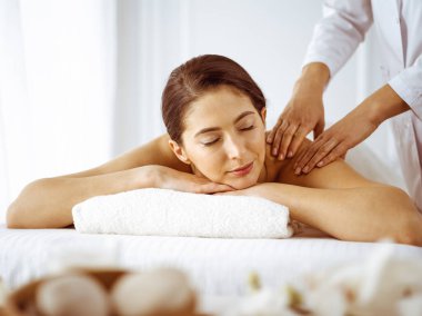 Güzel esmer kadın gözleri kapalı sırt masajından hoşlanıyor. Spa ve tıp konsepti