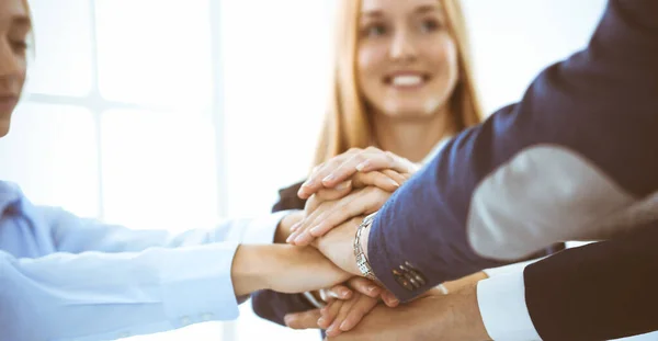 Business team showing unity with their hands together. Group of people joining hands and representing concept of friendship, teamwork and partnership