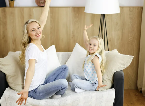 Mutlu bir aile. Sarışın genç anne sevimli kızıyla oynuyor ve sarılıyor. Annelik kavramı