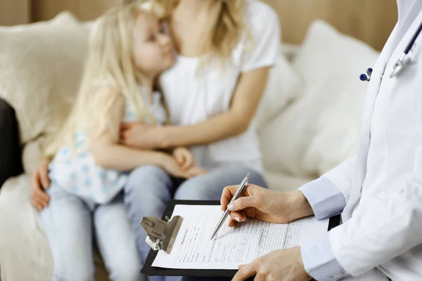 Dokter en patiënt. Kinderarts die klembord gebruikt terwijl ze het kleine meisje onderzoekt met haar moeder thuis. Ziek en ongelukkig kind bij medisch onderzoek. Geneesmiddelenconcept — Stockfoto