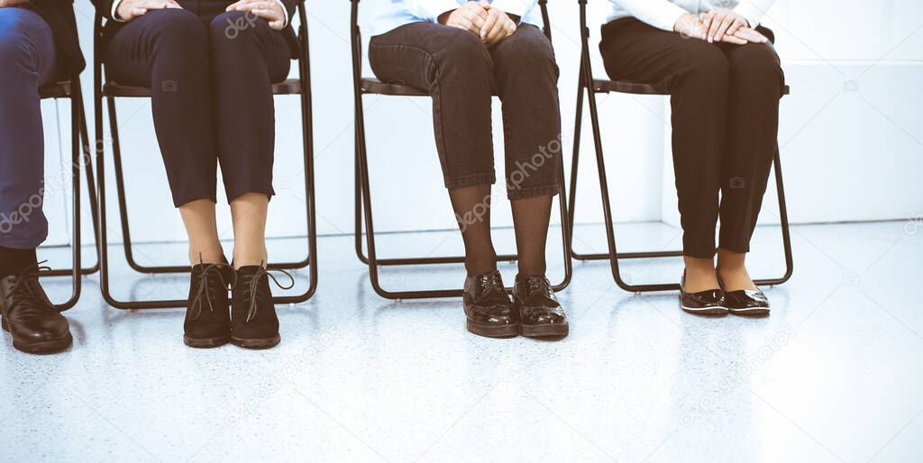 Group of business people sitting in office and waiting for job interview while using gadgets, close-up. Recruiting and headhunting concepts