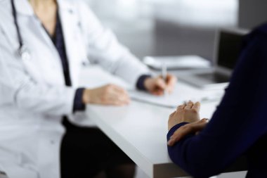 Bilinmeyen kadın-doktor, bir klinikteki dolapta birlikte otururken hastasına bazı tıbbi tavsiyeler yazıyor. Hekim bir dosya kullanıyor, yakın plan. Mükemmel.
