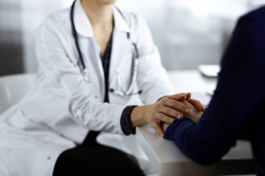 Bilinmeyen kadın doktor, kadın hastasına güvence veriyor, yakın plan. Doktor bir kadına danışmanlık yapıyor ve tavsiyelerde bulunuyor. Tıbbi ahlak ve güven kavramları. Tıpta empati