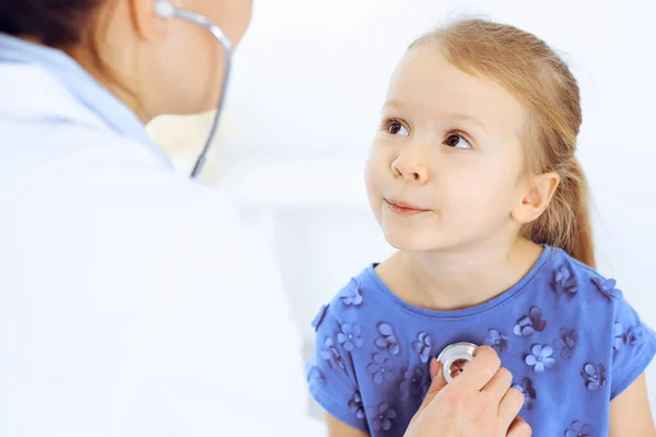 Doctor examinando a una niña por estetoscopio. Feliz niño sonriente paciente en la inspección médica habitual. Medicina y conceptos sanitarios — Foto de Stock