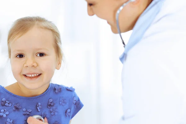 Doutor examinando uma menina por estetoscópio. Paciente de criança sorridente feliz em inspeção médica habitual. Conceitos de medicina e saúde — Fotografia de Stock