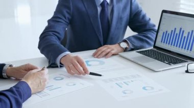 Finansal analizleri inceleyen profesyonel ekip, işbirlikçi toplantı sırasında basılı raporları ve dijital çizelgeleri inceliyor. İş adamları ve finans kavramı