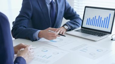 Finansal analizleri inceleyen profesyonel ekip, işbirlikçi toplantı sırasında basılı raporları ve dijital çizelgeleri inceliyor. İş adamları ve finans kavramı