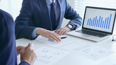 Bir dizüstü bilgisayarda finansal verileri tartışan çok sayıda iş arkadaşından oluşan bir ekip, görevdeki grafikleri ve pazar eğilimlerini analiz ediyor. İş adamları ve finans kavramı.