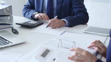 Profesyonel muhasebeciler finansal verileri analiz ediyor, hesap makinesindeki sayıları hesaplıyor, modern işyerindeki bilgisayar ve hesap çizelgelerini inceliyor. İş dünyasında denetim ve vergi teması