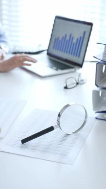 Muhasebeciler mali raporları büyüteç ve belgelerle inceliyor, muhasebe ve denetleme görevlerini yerine getiriyor, kapatın. Ticarette denetim ve vergiler.