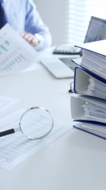 İki profesyonel muhasebeci büyüteç ve belgelerle mali raporları analiz ediyor, muhasebe ve denetleme işlerini ofiste yapıyor. Ticarette denetim ve vergiler.