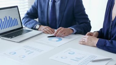 Şirket meslektaşları finansal raporları analiz ediyor, dizüstü verileri inceliyor ve stratejik planlama oturumunda işbirliği yaparken çizelgeleri basıyor. İş adamları ve finans kavramı