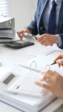 Ekonomik belgeleri analiz eden, hesap makineleri ve dizüstü bilgisayarlar kullanan iş adamları modern ofiste proje üzerinde birlikte çalışıyorlar. Denetim ve vergi kavramı.