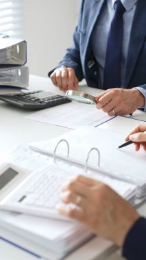 Ekonomik belgeleri analiz eden, hesap makineleri ve dizüstü bilgisayarlar kullanan iş adamları modern ofiste proje üzerinde birlikte çalışıyorlar. Denetim ve vergi kavramı.