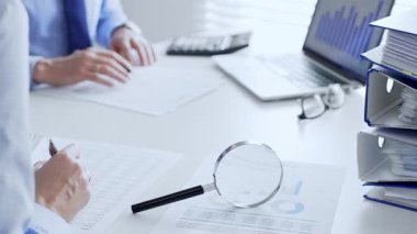 Muhasebeciler mali raporları büyüteç ve belgelerle inceliyor, muhasebe ve denetleme görevlerini yerine getiriyor, kapatın. Ticarette denetim ve vergiler.