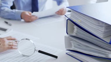 Muhasebeciler mali raporları büyüteç ve belgelerle inceliyor, muhasebe ve denetleme görevlerini yerine getiriyor, kapatın. Ticarette denetim ve vergiler.