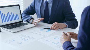 İş adamı, görevdeki tablolar ve piyasa eğilimlerini incelerken kadın ortağıyla birlikte dizüstü bilgisayarda mali verileri tartışıyor. İş adamları konsepti.