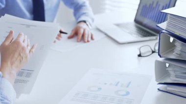 Ofis çalışanları ya da denetçiler mali raporları analiz ediyor ve ön planda bir yığın mavi klasörle beyaz masada otururken belgeleri kontrol ediyorlar. İş dünyasında denetim ve vergi teması.