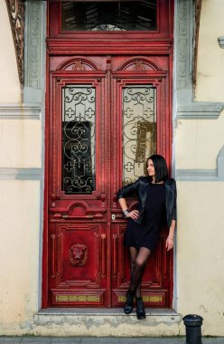 Siyah deri ceketli esmer kadın eski kırmızı kapının yanında duruyor. Rock konsepti. Batumi, Georgia 'daki kız model..