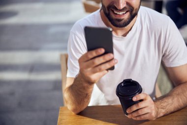 Kahve masasında oturan ve akıllı telefonları kapatmaya çalışan bir adam yüzü.