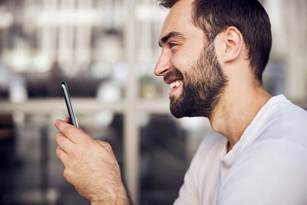 Waist up portrait of smiling man with smartphone outdoor a side view