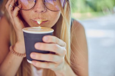 Kırpılmış, güzel, kızıl saçlı, çilli, kahve içen ve kafede rüya gören bir kız.