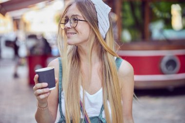 Güzel gülümseyen kızıl saçlı, çilli ve gözlüklü güzel kızın belinde bir fincan kahve tutuyor ve yakından bakıyor.