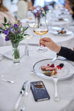 Vip RestarAunt 'ın elinde beyaz şarap kadehi var.