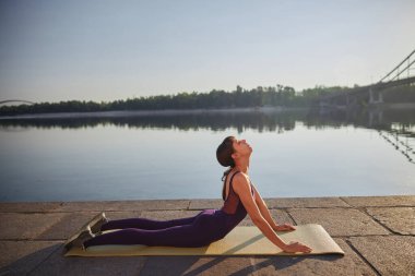 Yoga yapan genç bir kadının yan görüntüsü. Kobra pozu.