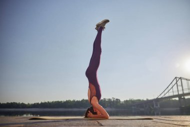 Sabah yogası sırasında amuda kalkan güzel bir kadının yan görüntüsü.