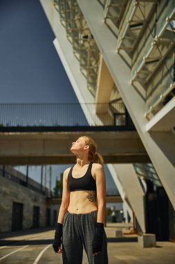 Eğitimden sonra güneşli ışıkların tadını çıkaran atletik genç bir kadın. 