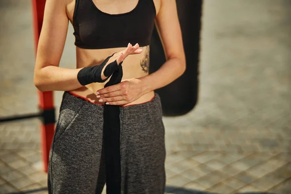 Cropped shot of beautiful fit young woman who is with black hand wraps on the sports ground