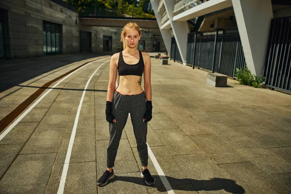 Sıkı çalışmadan sonra poz veren ve doğrudan kameraya bakan güzel ve fit bir kadın.