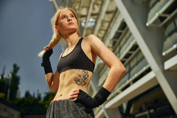 Gökyüzüne bakarken kickboks antrenmanından önce rüya gören atletik genç bir kadın.